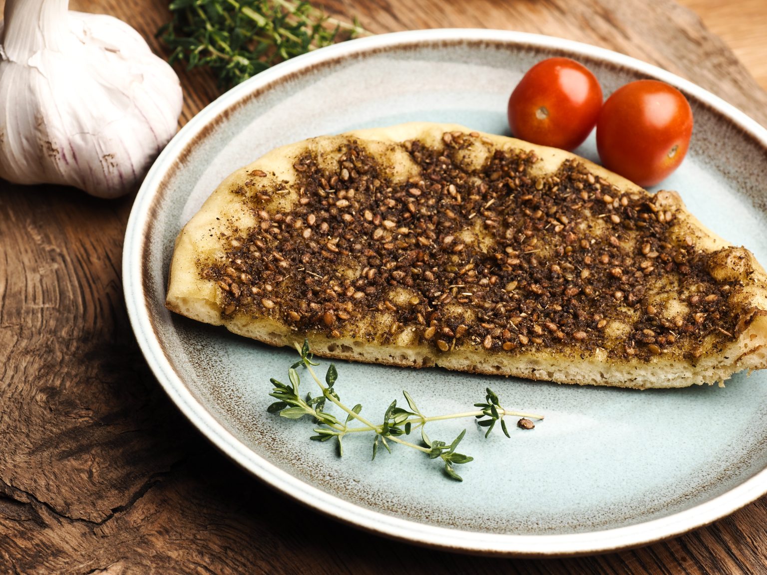 Tasty manaqish with thyme and sesame on a rustic blue ceramic plate
